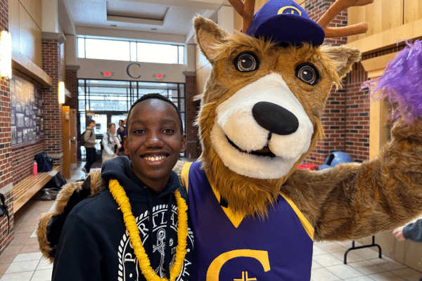 student with mascot smiling in hallway