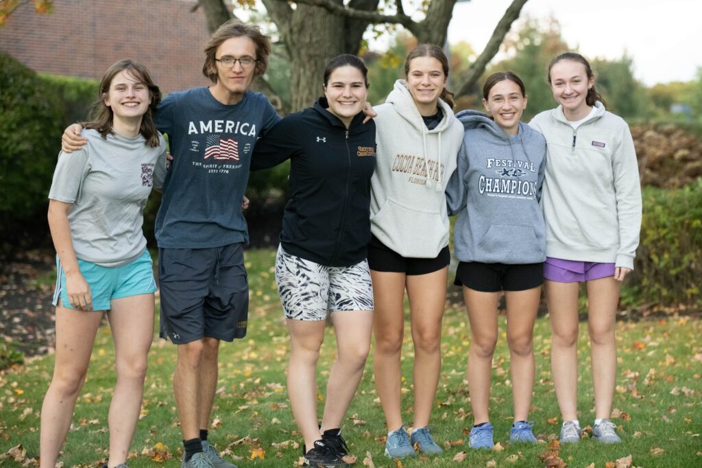 group of students smiling outside wearing sweatshirts and shorts