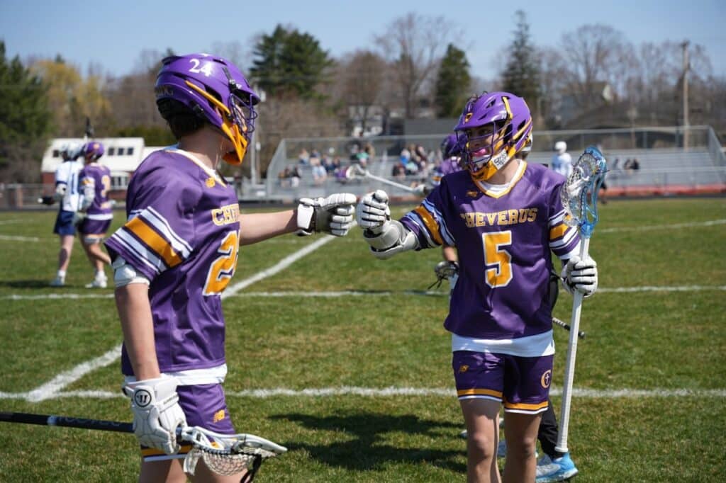 two lacrosse players fist bumping