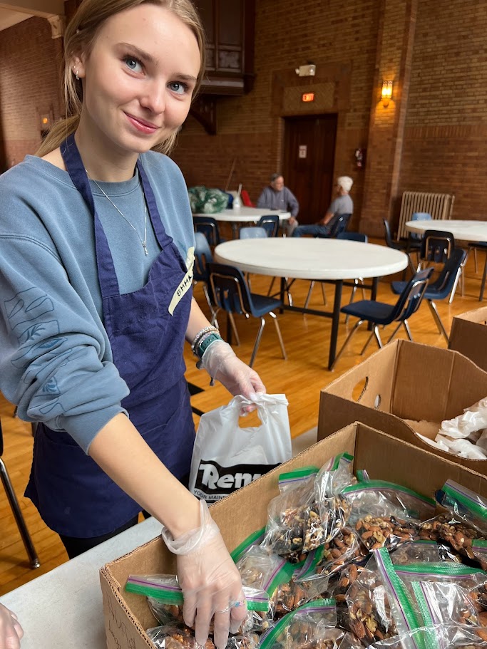student smiling as she volunteers and preps food
